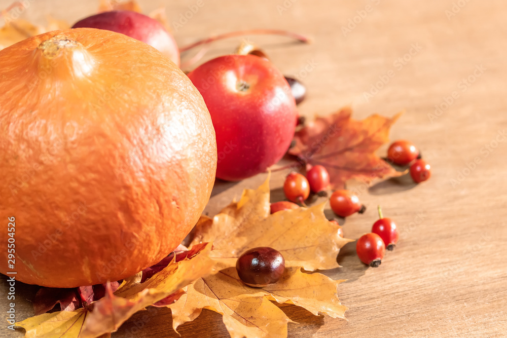 Autumn, autumn leaves, pumpkin and apples on a wooden table background.