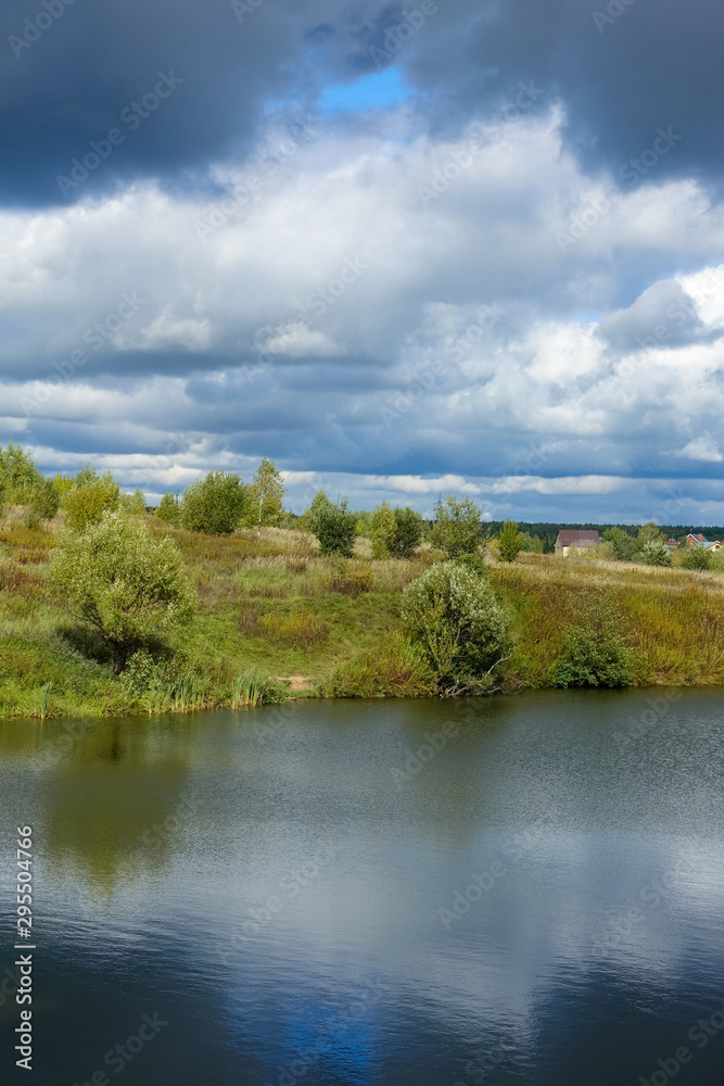Beautiful rain clouds in the sky over the river and the steppe in the fall.