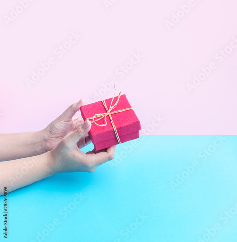 Young woman hand holding colorful gift box on pastel color background.anniversary and christmas