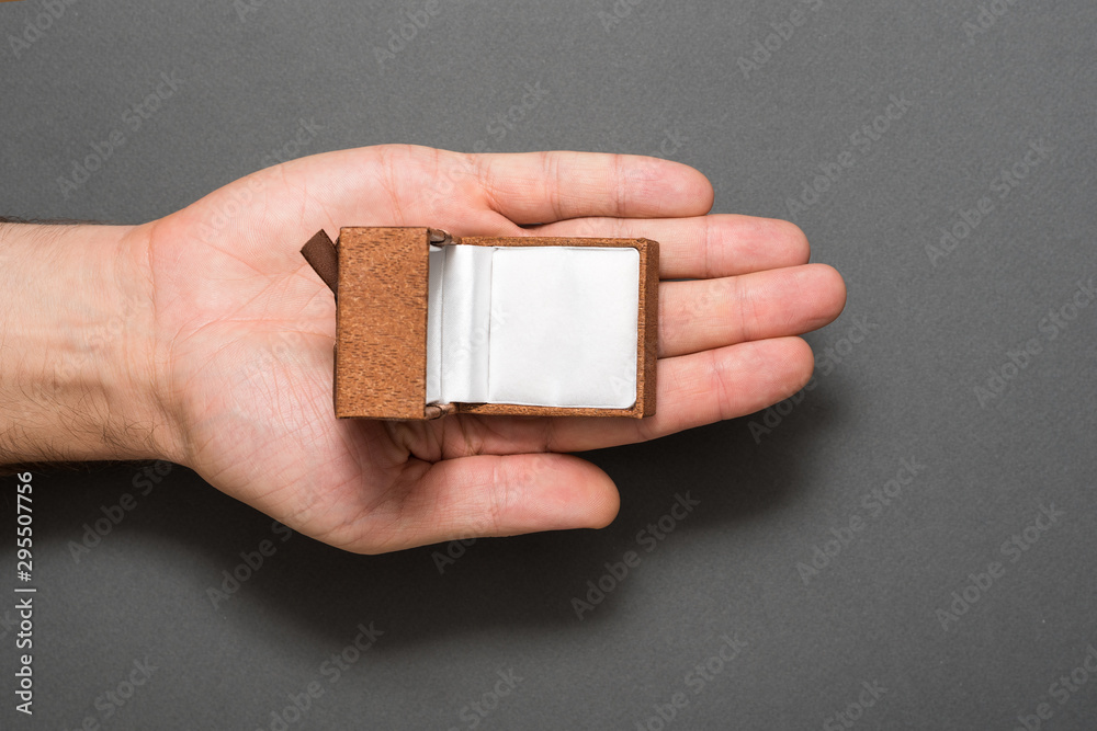 Fototapeta premium Male palm with an empty open brown jewelry box. Present. Black background