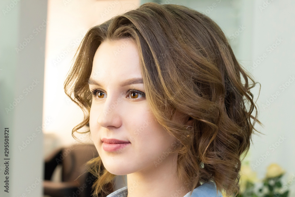 Girl with curled hair sitting in a chair in a beauty studio. Girl with curled hair sitting in a chair in a beauty studio.