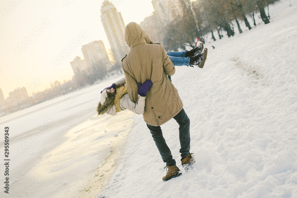 Theme outdoor activities in winter. Loving couple man and woman Caucasian joy happiness happiness love emotions on the shore of the lake. The guy wears holdings a girl