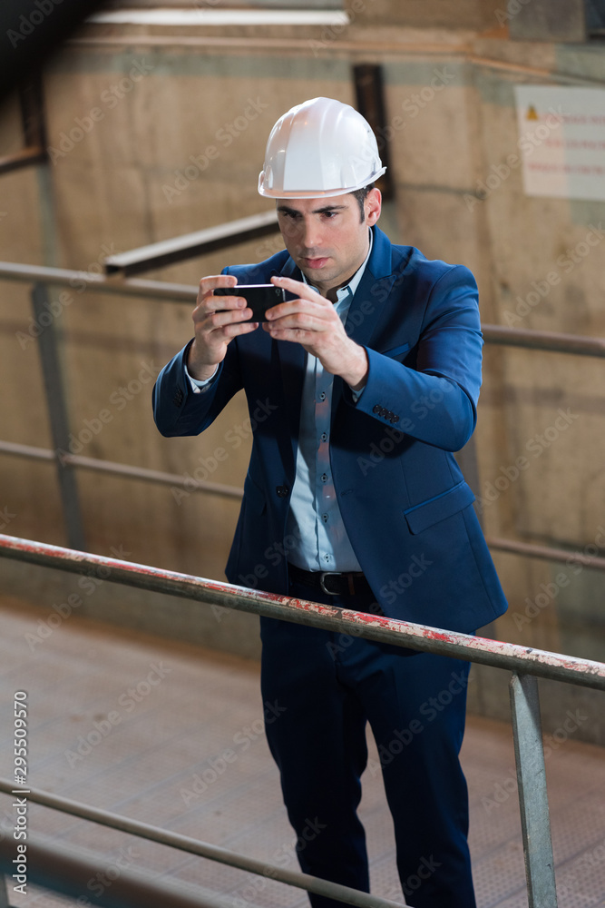 suited male worker taking photograph stood behind railings