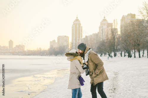 Theme love and date on nature. Young Caucasian heterosexual couple boy and girl kiss hugging warm scarf in winter near a frozen lake in winter. Bearded Man Hugging Woman. Valentine's day holiday