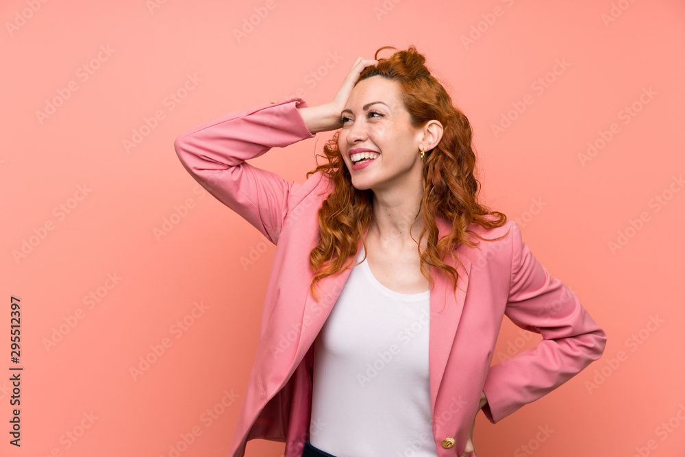 Redhead woman in suit over isolated pink wall laughing Redhead woman in suit over isolated pink wall laughing