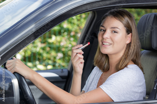 young good-looking woman applying lipstick in car © auremar