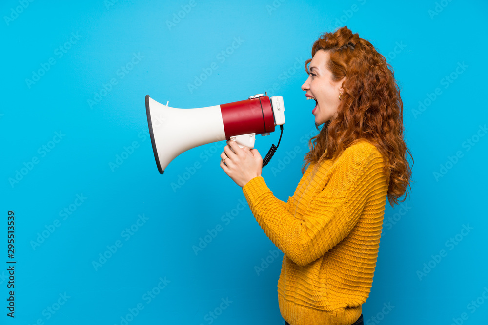 Redhead woman with yellow sweater shouting through a megaphone Redhead woman with yellow sweater shouting through a megaphone