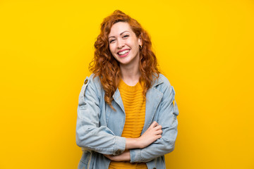 Redhead woman over isolated yellow background laughing