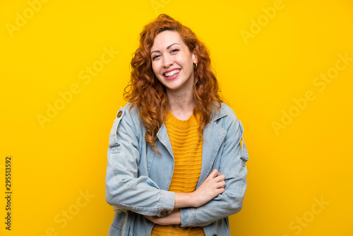 Redhead woman over isolated yellow background laughing