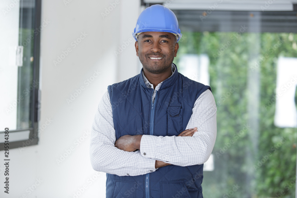 happy young man builder in helmet standing with arms crossed happy young man builder in helmet standing with arms crossed