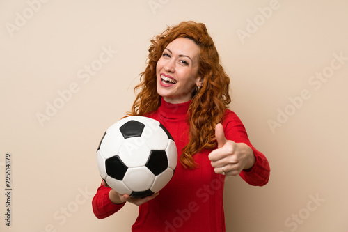 Redhead woman with turtleneck sweater holding a soccer ball © luismolinero