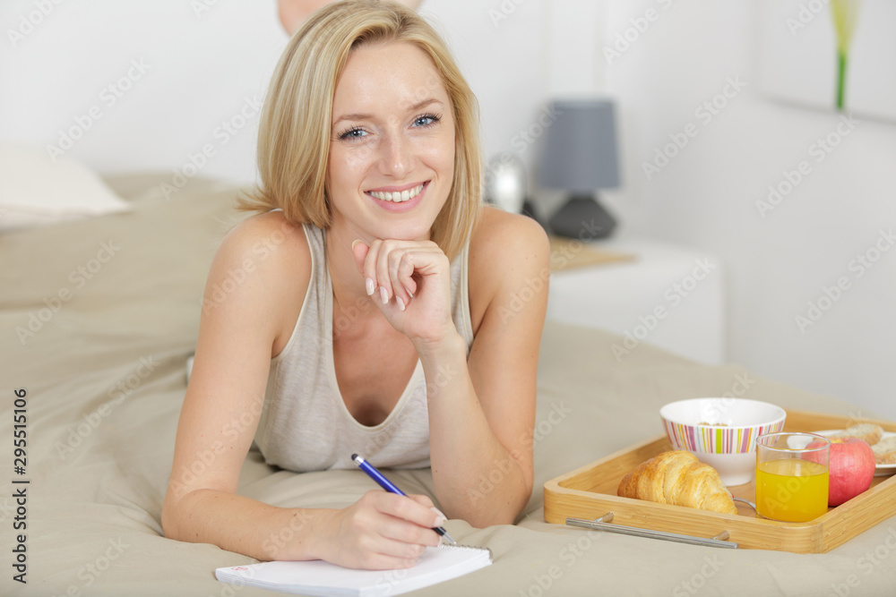 happy young woman with tray on the bed