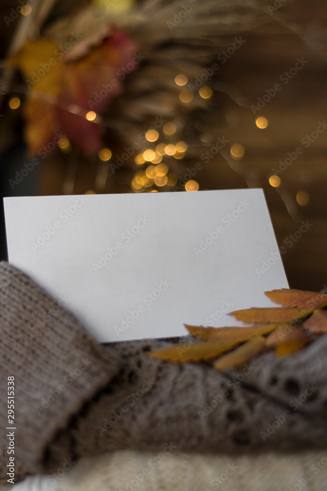 Stack of cozy knitted sweaters on a wooden table with in the greeting card with place for text. background bokeh of lights. Retro style. Warm concept. close up