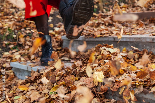 Wallpaper Mural A girl in black boots and a red coat kicks yellow and red foliage strolling in the park alone on a clear autumn day during a fall. Freshness, nature and fun. Torontodigital.ca