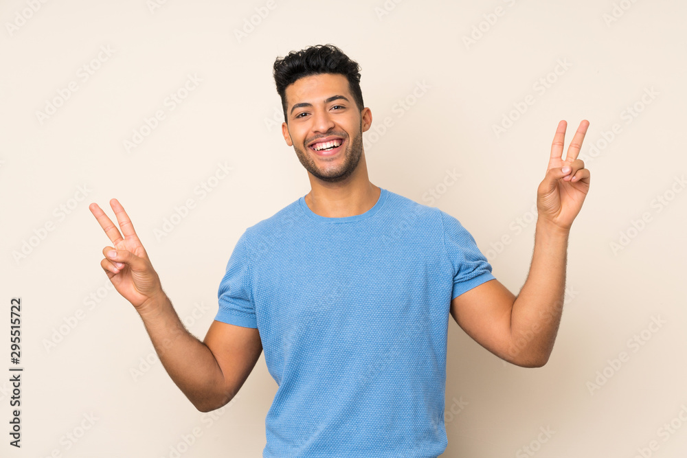 Young handsome man over isolated background showing victory sign with both hands Young handsome man over isolated background showing victory sign with both hands
