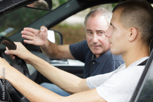 father teaching teenage son to drive