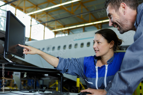 Canvas Print female aircraft mechanic pointing at laptop