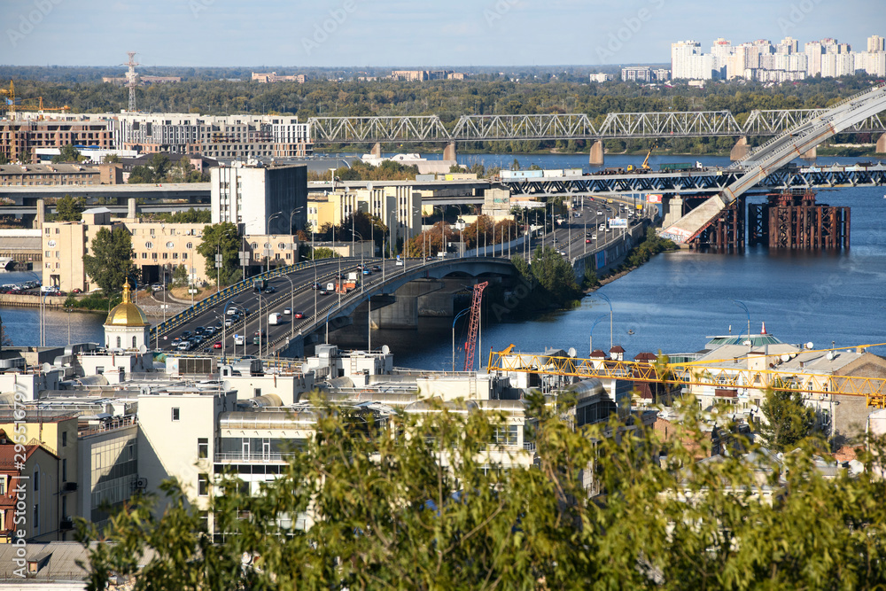 Obraz premium View of the old Podil district of the city of Kyiv and Dnipro River Dnieper with bridges. Ukraine, September 2019