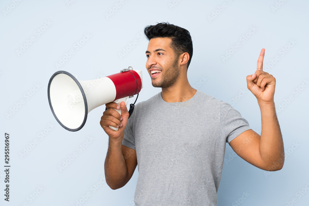 Young handsome man over isolated background shouting through a megaphone Young handsome man over isolated background shouting through a megaphone