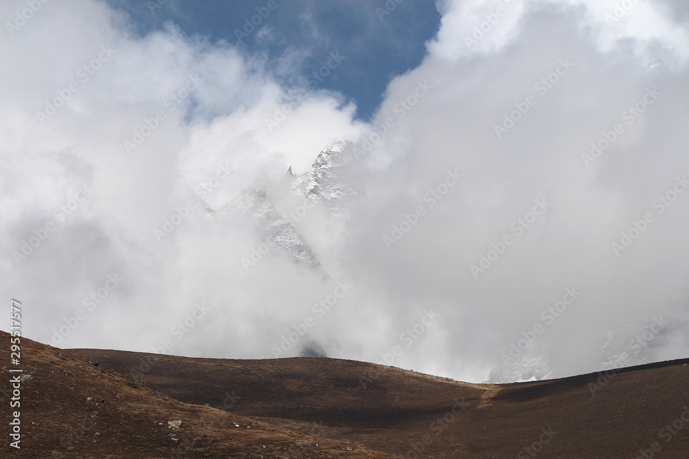 Kyajo Ri mountain peak is visible through dense white clouds in Himalayas in Sagarmatha national park in Nepal near Lunden village. On the way to Everest base camp through Gokyo lakes.