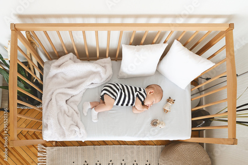 Top view of adorable newborn baby sleeping in wooden crib photo