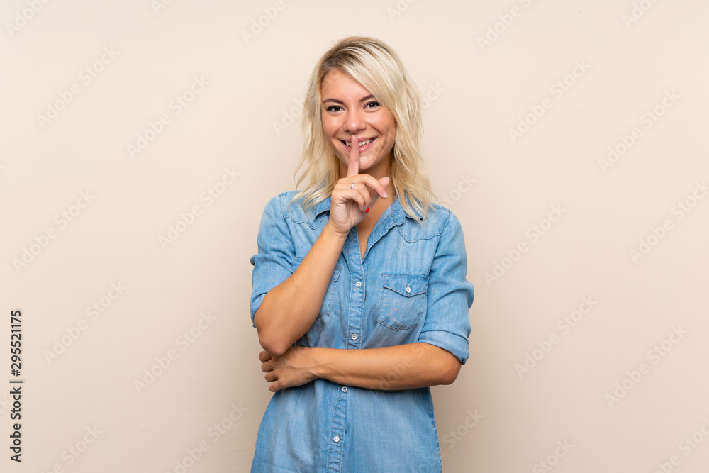 Young blonde woman over isolated background doing silence gesture Young blonde woman over isolated background doing silence gesture