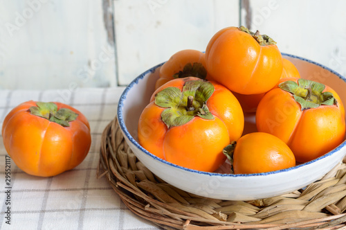 ripe persimmon fruit, isolated on white wooden background photo