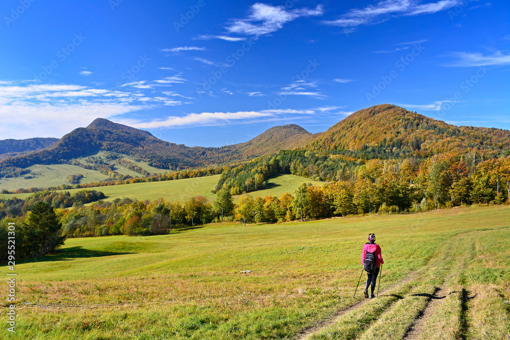Woman backpacker on hiking trail in the mountains in autumn sunny day