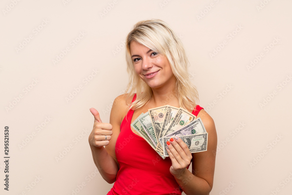 Young blonde woman over isolated background taking a lot of money Young blonde woman over isolated background taking a lot of money