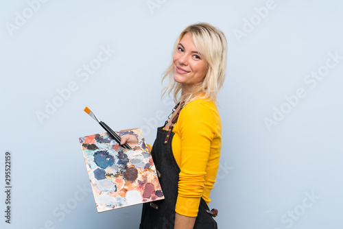 Young blonde woman over isolated background holding a palette