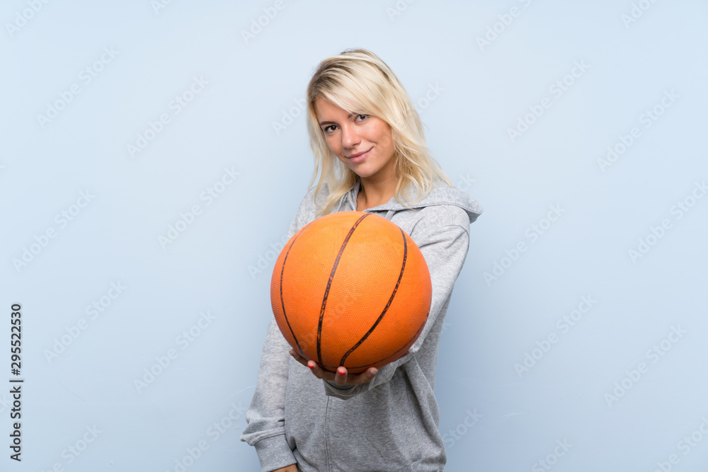 Young blonde woman over isolated background with ball of basketball