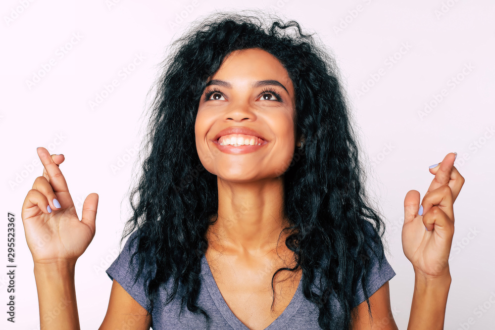 Wishing for luck. Portrait of content African American woman looking up with happy face expression and with her fingers crossed. Wishing for luck. Portrait of content African American woman looking up with happy face expression and with her fingers crossed.