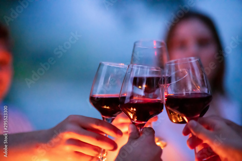 Photography friends toasting red wine glass during french dinner party outdoor