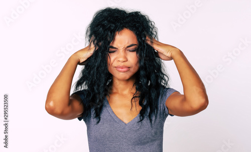 Feeling overwhelmed. Close-up photo of stressed African American woman standing in front of the camera with her hands touching temples indicating headache or nervousness.