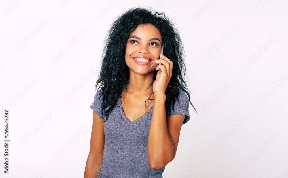 Great news! Overjoyed young African American lady is smiling kindly and looking to the left upper corner while talking on the cellphone. Great news! Overjoyed young African American lady is smiling kindly and looking to the left upper corner while talking on the cellphone.