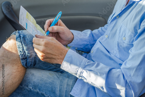 man in blue shirt and blue jeans writing part of accident inside the car