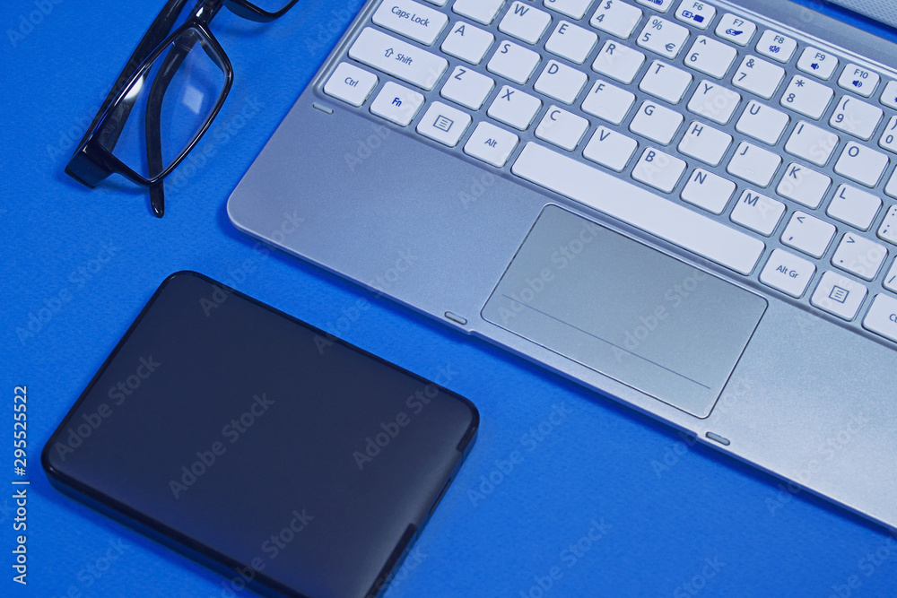 Fototapeta premium A portable hard drive and a laptop. Business mockup with blue background