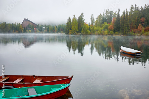 Foggy autumn Strbske lake with refletion and boats on the water in High Tatras National Park, Slovakia