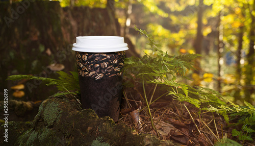 Cup of coffee on the stump in the forest. Autumn, fall concept. Moody picture, flare