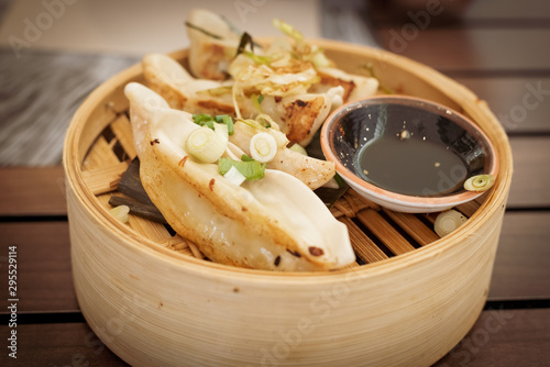 Thai food. mixed chicken, shrimp and vegetable gyozas in a Thai steamer with soy sauce in a black bowl photo