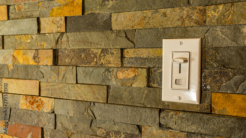 A light switch on a tiled stone wall