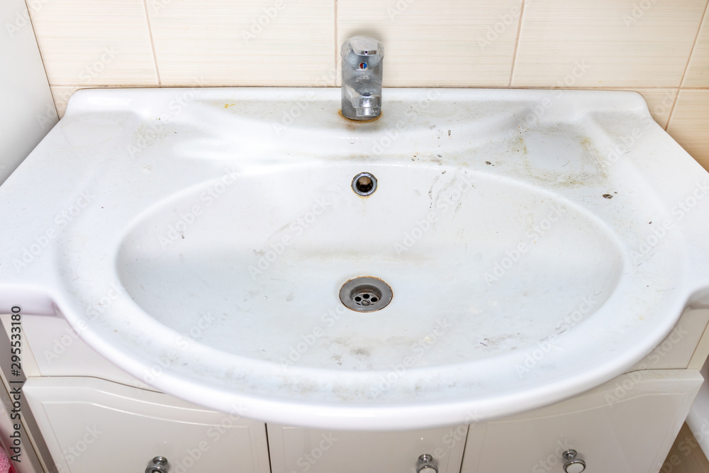 Old dirty washbasin with rust stains, limescale and soap stains in the bathroom with a faucet, water tap Old dirty washbasin with rust stains, limescale and soap stains in the bathroom with a faucet, water tap