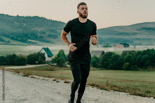 Man running / sprinting on road in mountains. Fit male fitness runner during outdoor workout. Young caucasian man.