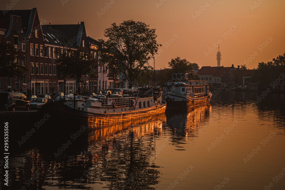 Sunrise over a canal at a windmill in the Netherlands Amsterdam. ships anchored in the port