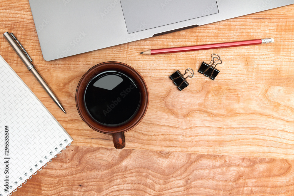 Work wooden office table with laptop, coffee cup, notepad and pen, top view Work wooden office table with laptop, coffee cup, notepad and pen, top view