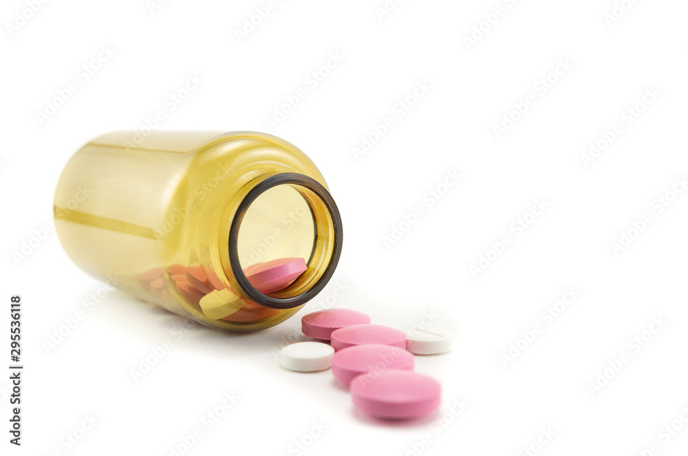 glass bottle for tablets isolated on a white background, tablets which have fallen out of the yellow container glass bottle for tablets isolated on a white background, tablets which have fallen out of the yellow container