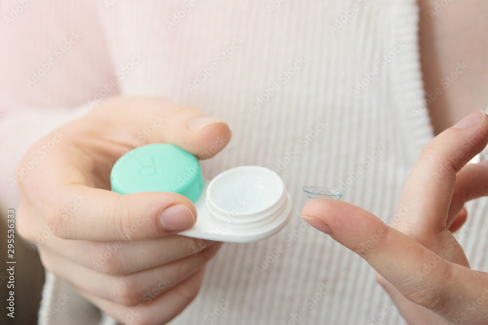 the girl is holding a container for soft contact lenses and a lens on her finger the girl is holding a container for soft contact lenses and a lens on her finger