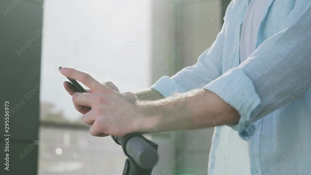 A guy with electric scooter using his phone outdoors A guy with electric scooter using his phone outdoors