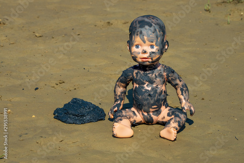 Doll sitting next to a sample of disgusting looking mud and is bedaubed with this therapeutic mud from a beach near Soline, Krk, Croatia photo