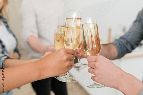 Hands of young multiracial friends clinking with flutes of sparkling champagne